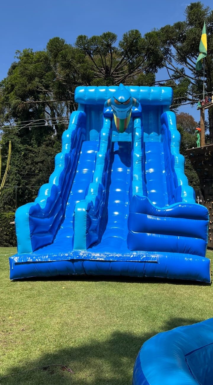 Tobogã inflável azul da W7 Diversões montado em um gramado